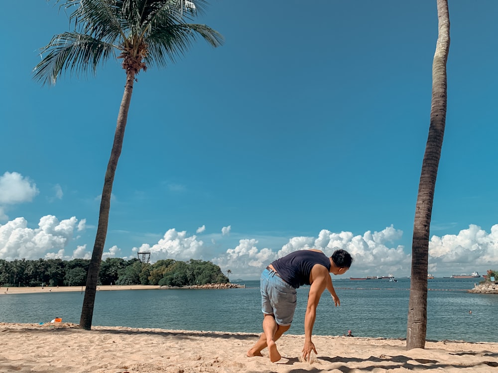 man in black t-shirt and blue denim shorts standing on beach shore during daytime