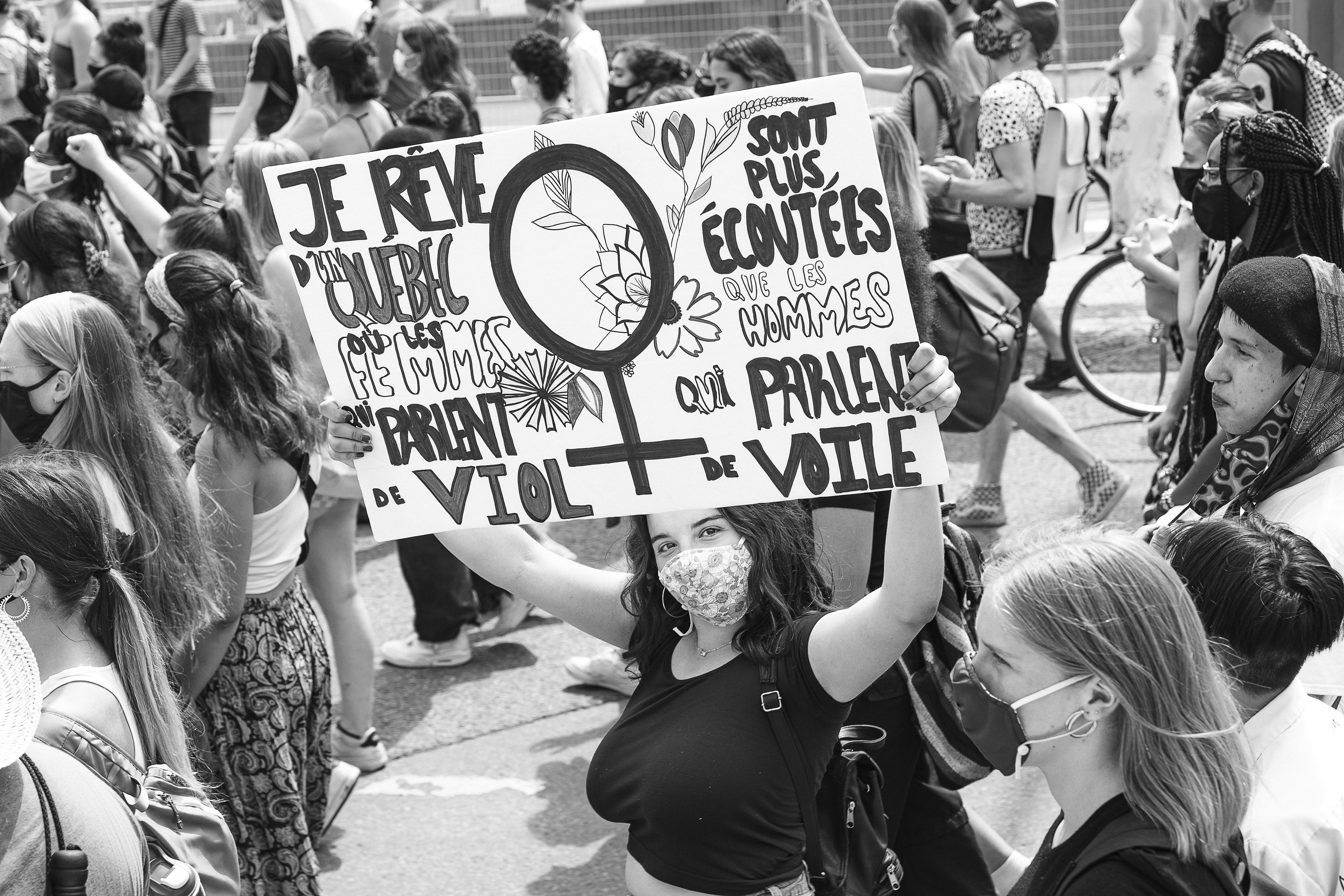 grayscale photo of woman holding white and blue signage