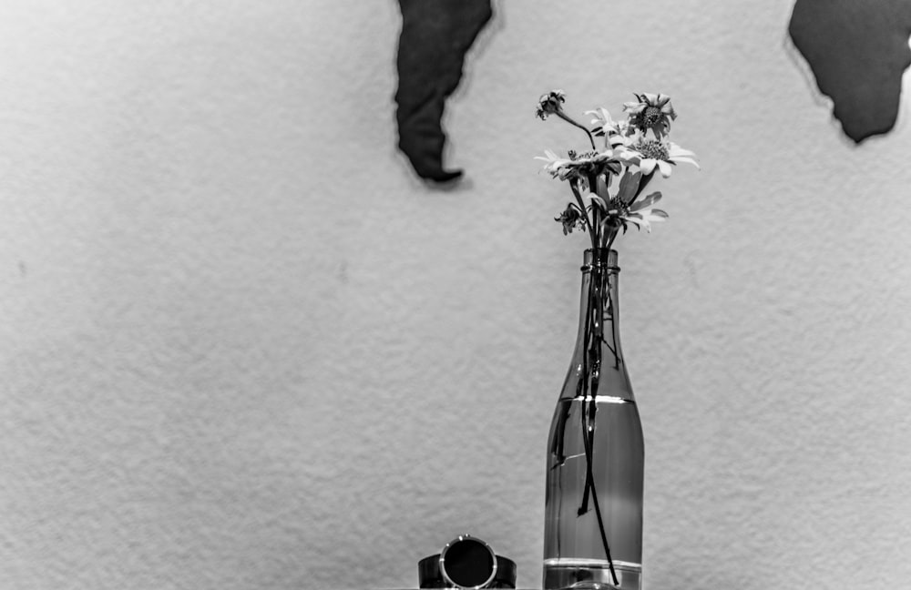 grayscale photo of person holding flower in glass vase