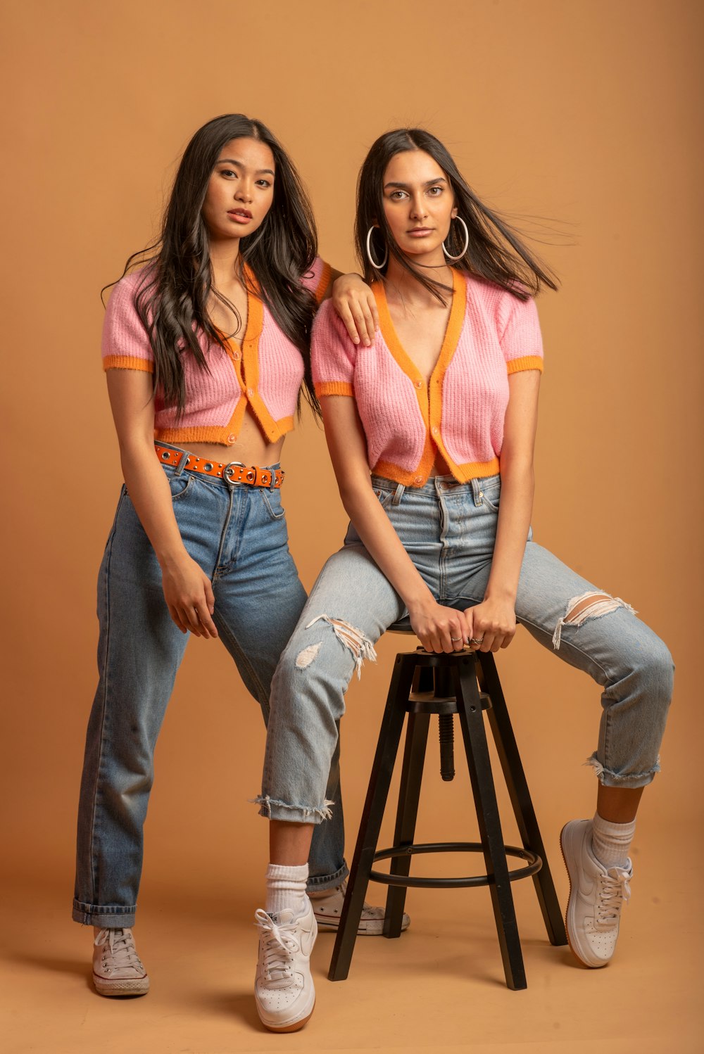 2 women wearing blue denim jeans and orange tank top