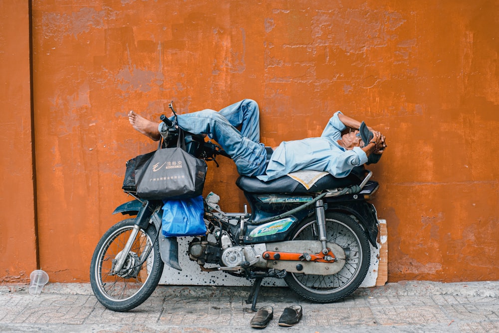 Hombre en chaqueta de mezclilla azul y jeans de mezclilla azul montando motocicleta negra