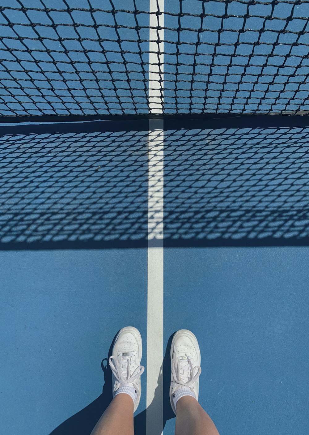 person in white sneakers standing on black and white stripe floor