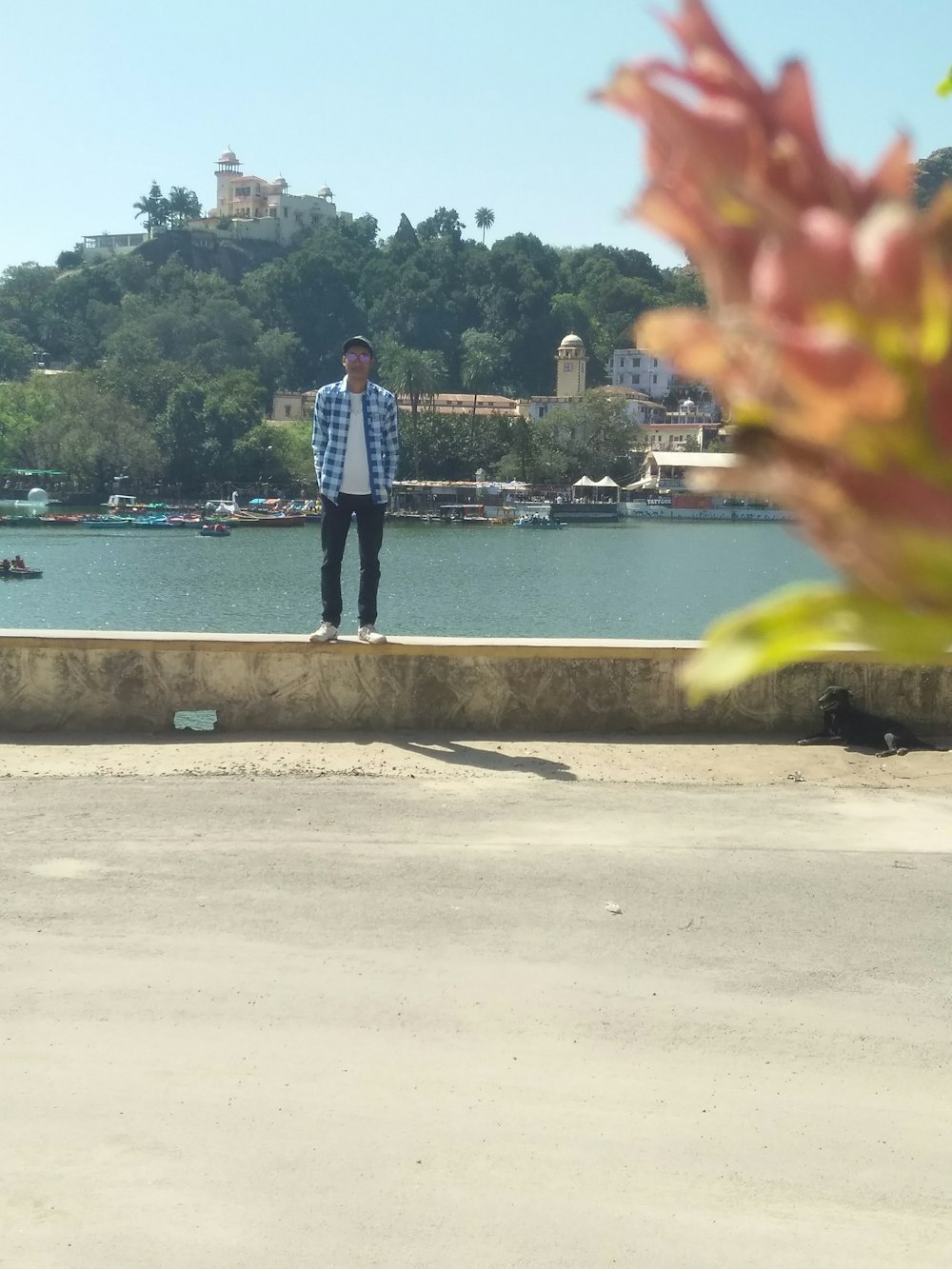 man in blue denim jeans standing on gray concrete pavement near body of water during daytime