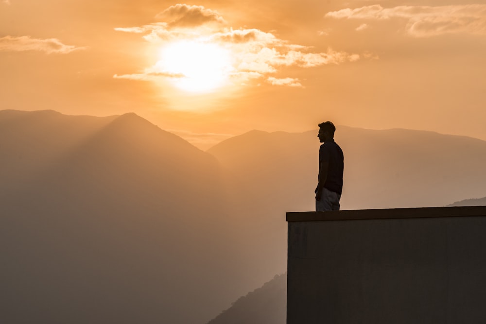 Silhouette eines Mannes, der bei Sonnenuntergang auf dem Dach des Gebäudes steht