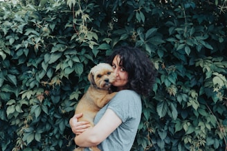 woman in gray t-shirt holding brown short coated dog