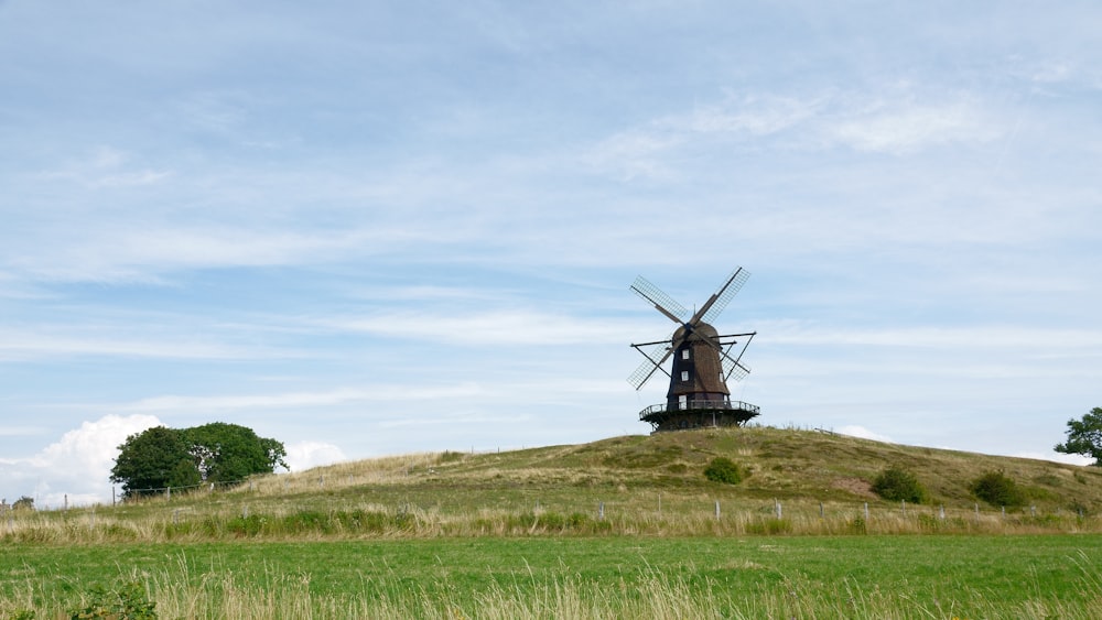 brown windmill on green grass field under white clouds during daytime