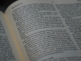 A close-up view of an open book, displaying text in a serif font. The text appears to be a narrative or dialogue. The focus is on the center of the page, with some text slightly blurred at the edges, suggesting depth of field.