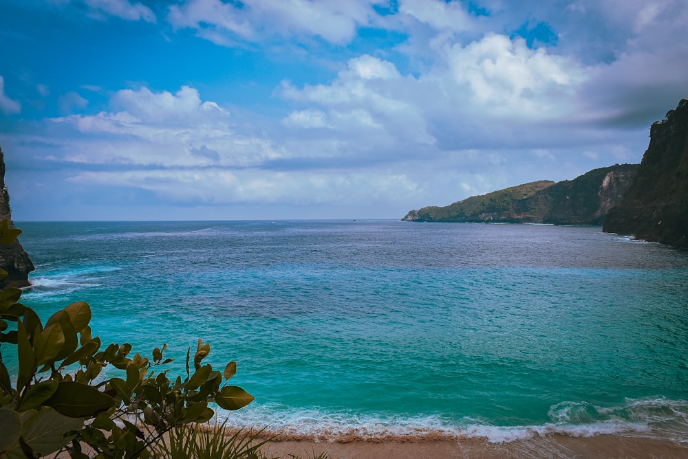 green island on blue sea under blue sky and white clouds during daytime