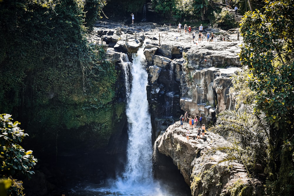 people sitting on rock near waterfalls during daytime