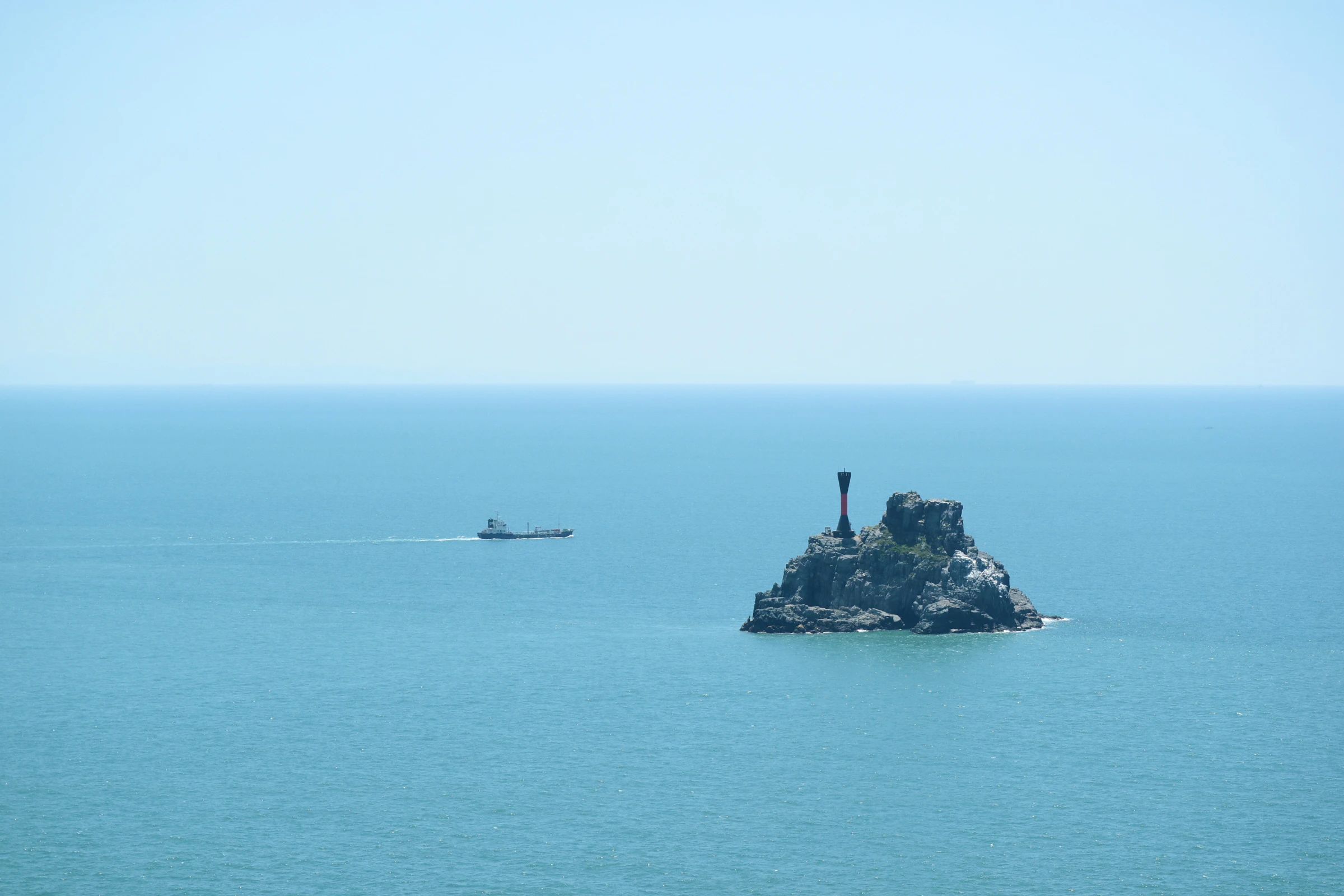 A small rocky island with a lighthouse seen from the cliffs of Taejongdae in Busan
