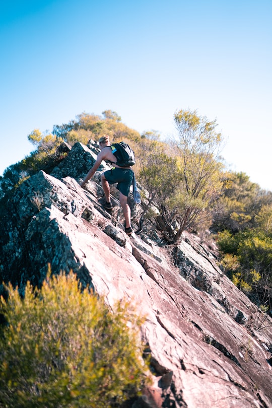 man in black t-shirt climbing on rocky mountain during daytime in Gold Coast Australia
