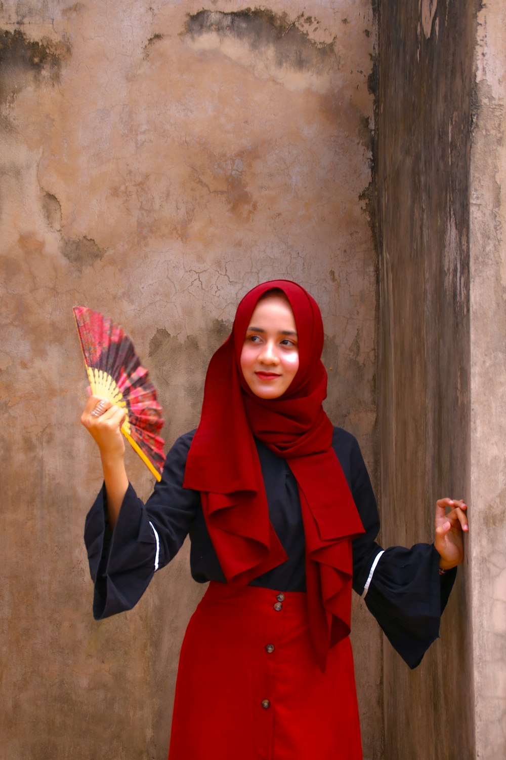 woman in red hijab and black long sleeve dress holding yellow and white umbrella