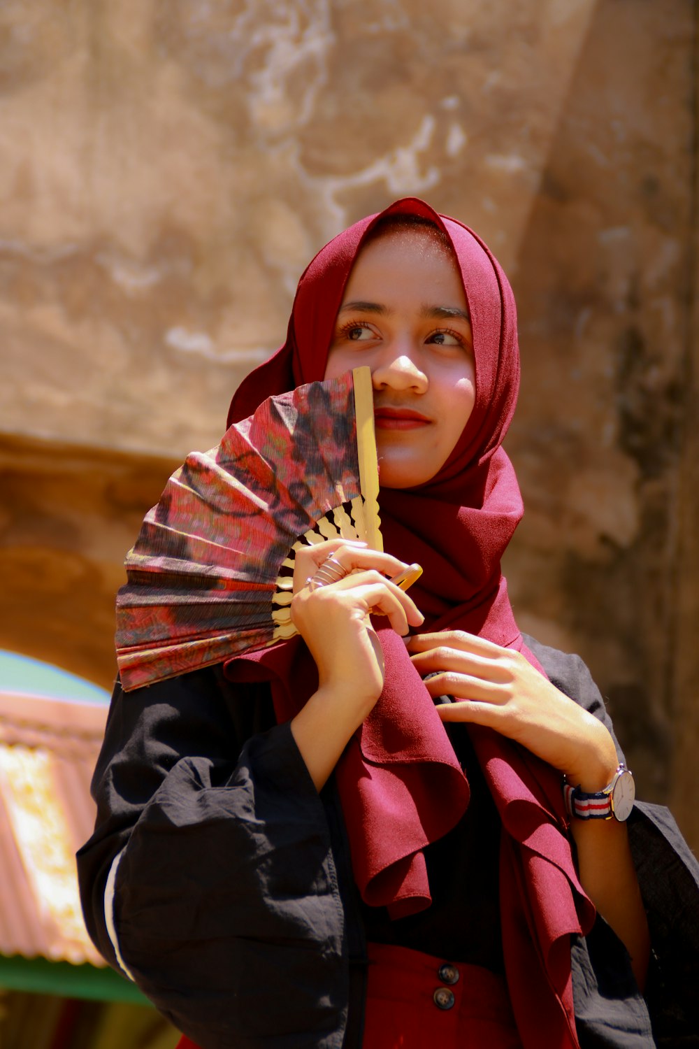 donna in hijab rosso che tiene il bastone di legno marrone