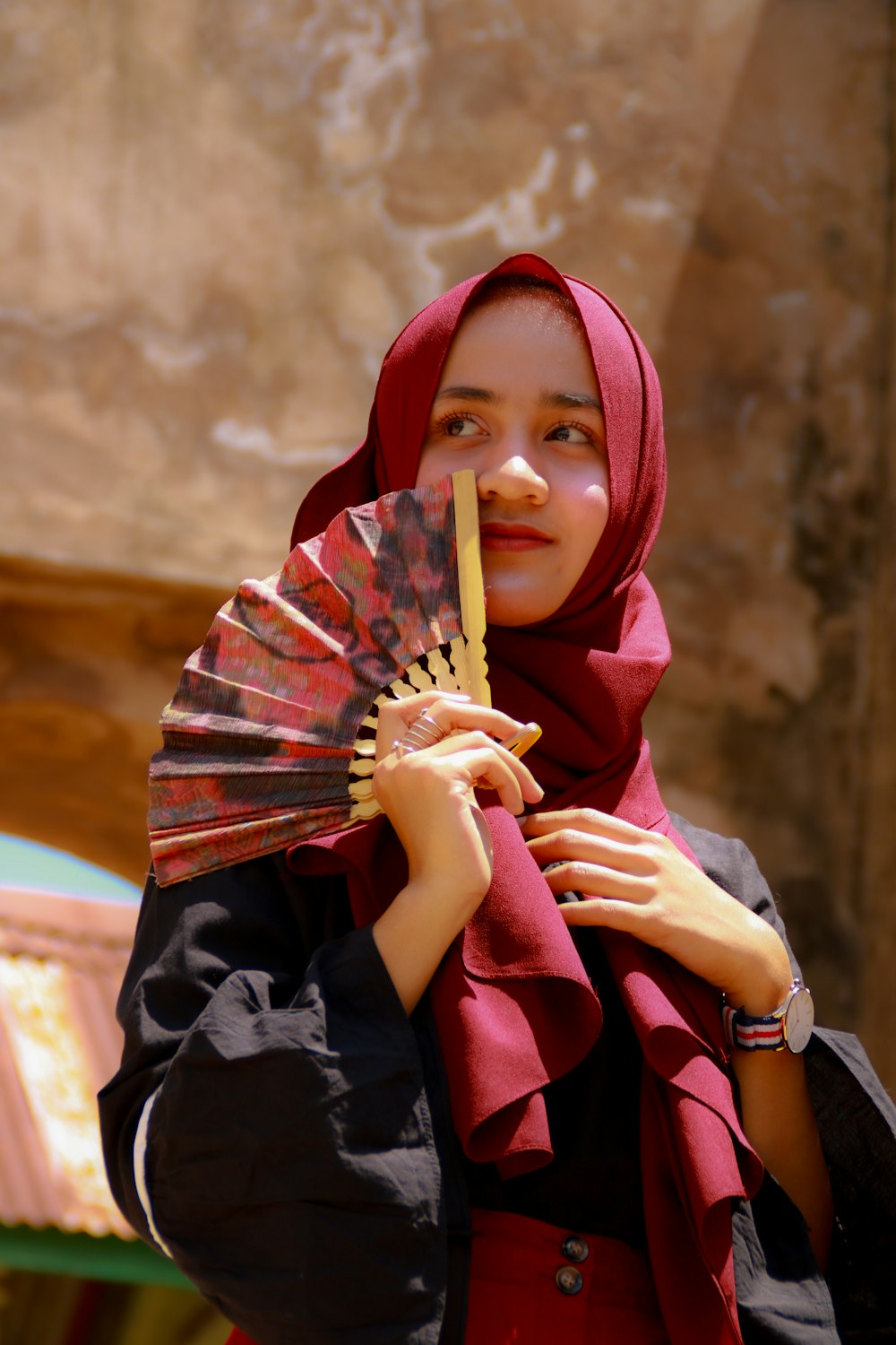 Femme en hijab rouge tenant un bâton en bois marron