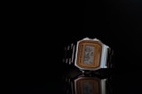 A vintage-style digital wristwatch with a rectangular face and a metallic band displayed against a dark background. The watch features a gold-tone frame around the face, with black detailing and digital numbers showing the time as 10:48:51.