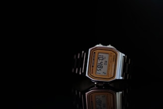A vintage-style digital wristwatch with a rectangular face and a metallic band displayed against a dark background. The watch features a gold-tone frame around the face, with black detailing and digital numbers showing the time as 10:48:51.