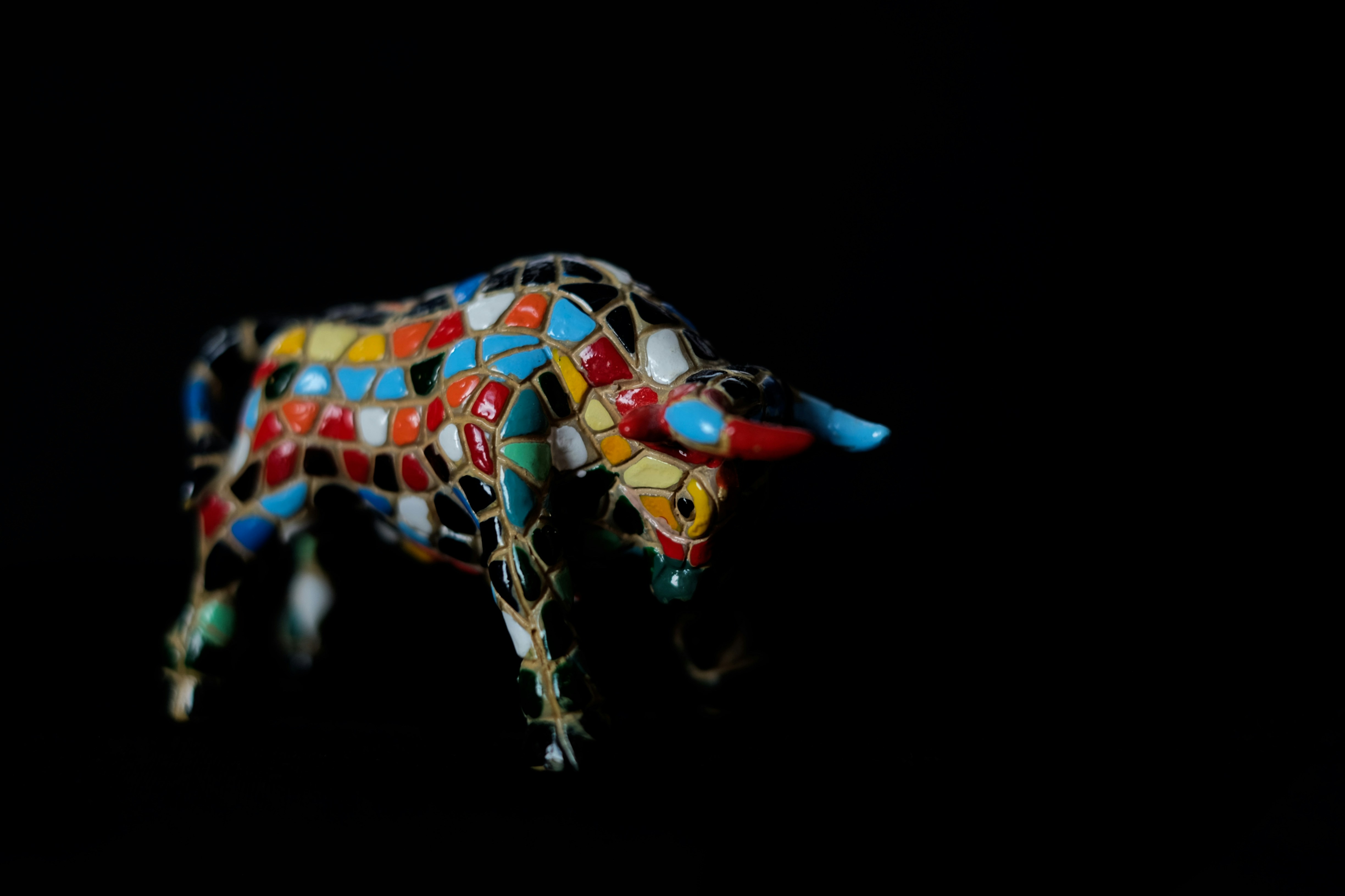 A colorful mosaic bull figurine on black background