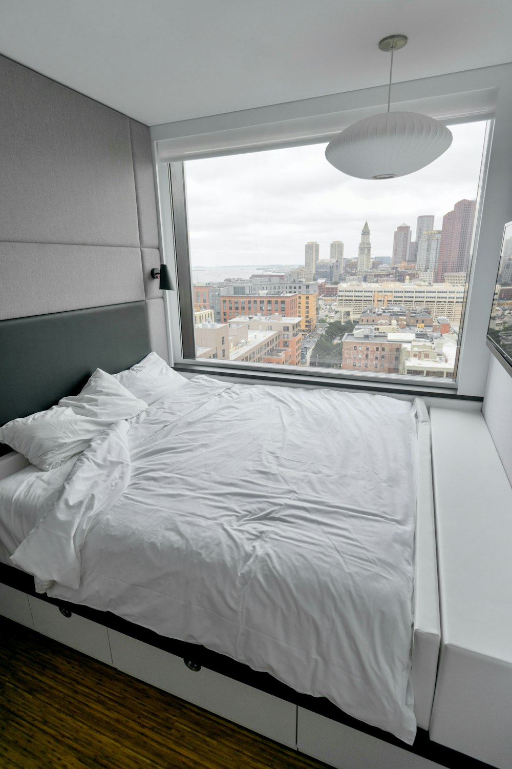 Weiße Bettwäsche in der Nähe von Glasfenster