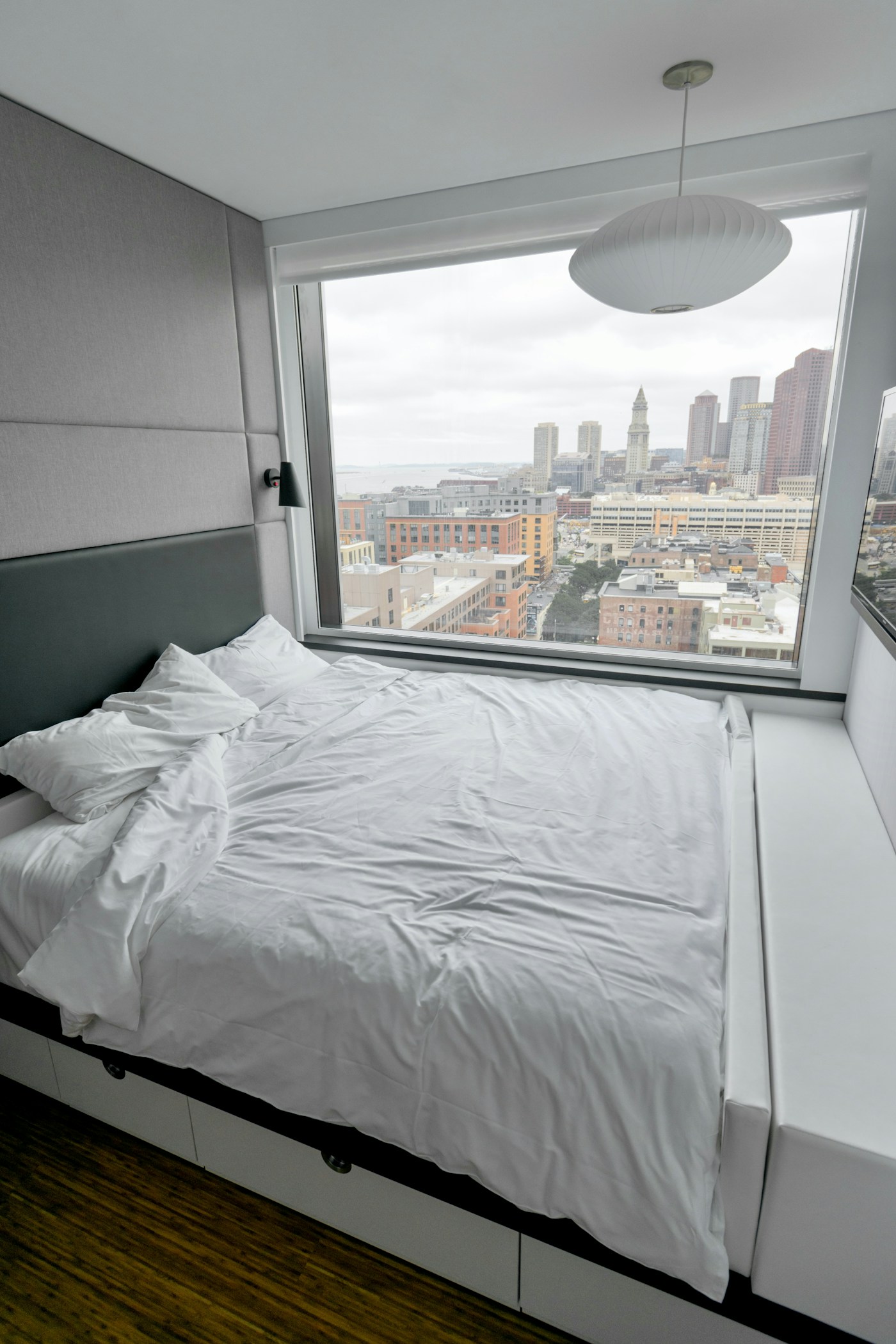 Hotel guest room with white bed linen positioned near a city-view window