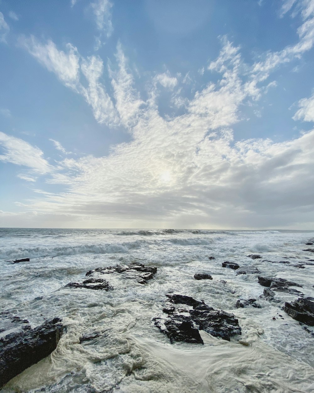 black rocks on sea under blue sky during daytime