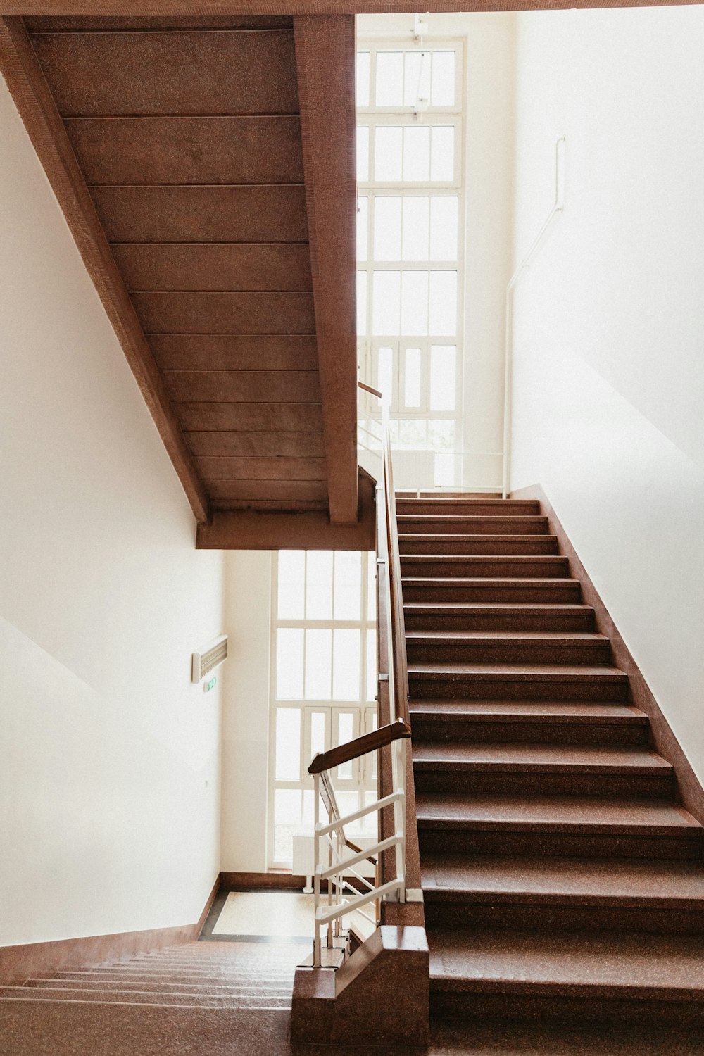 Escalera de madera marrón cerca de la pared blanca