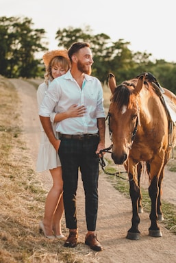 photography poses for couples,how to photograph woman in white button up shirt standing beside brown horse during daytime