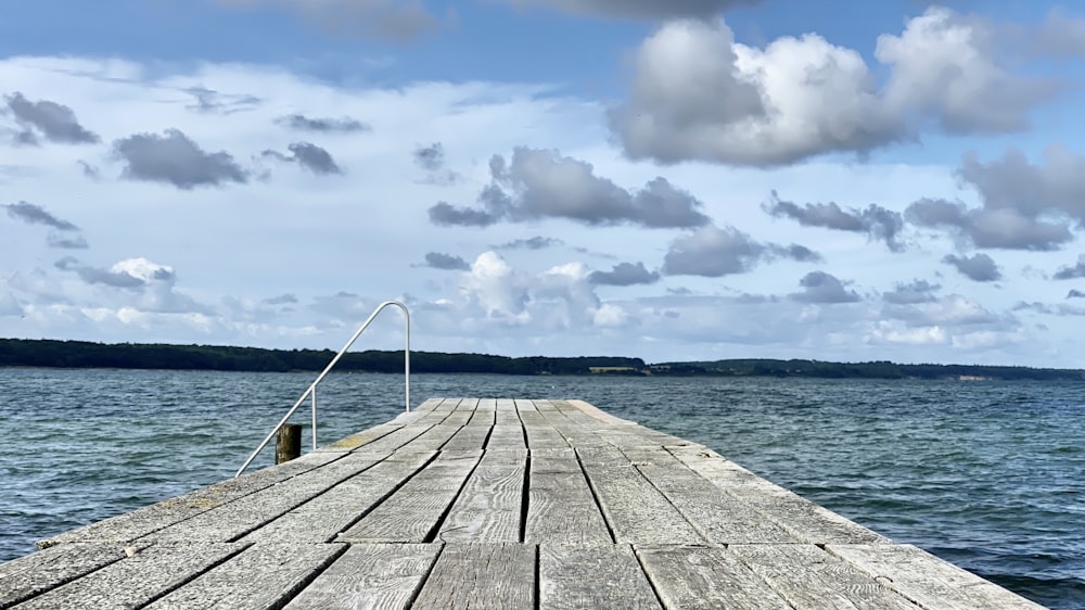 brown wooden dock on sea under white clouds during daytime