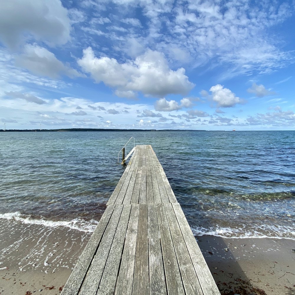 brown wooden dock on sea under blue sky during daytime