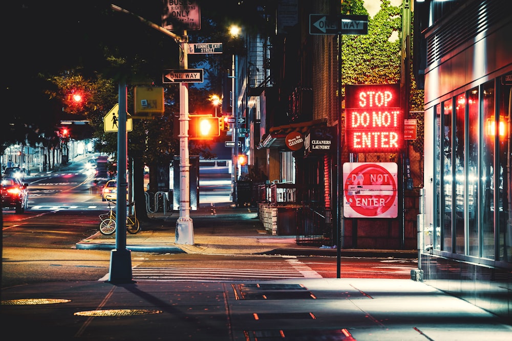 red and white stop light sign on sidewalk during night time