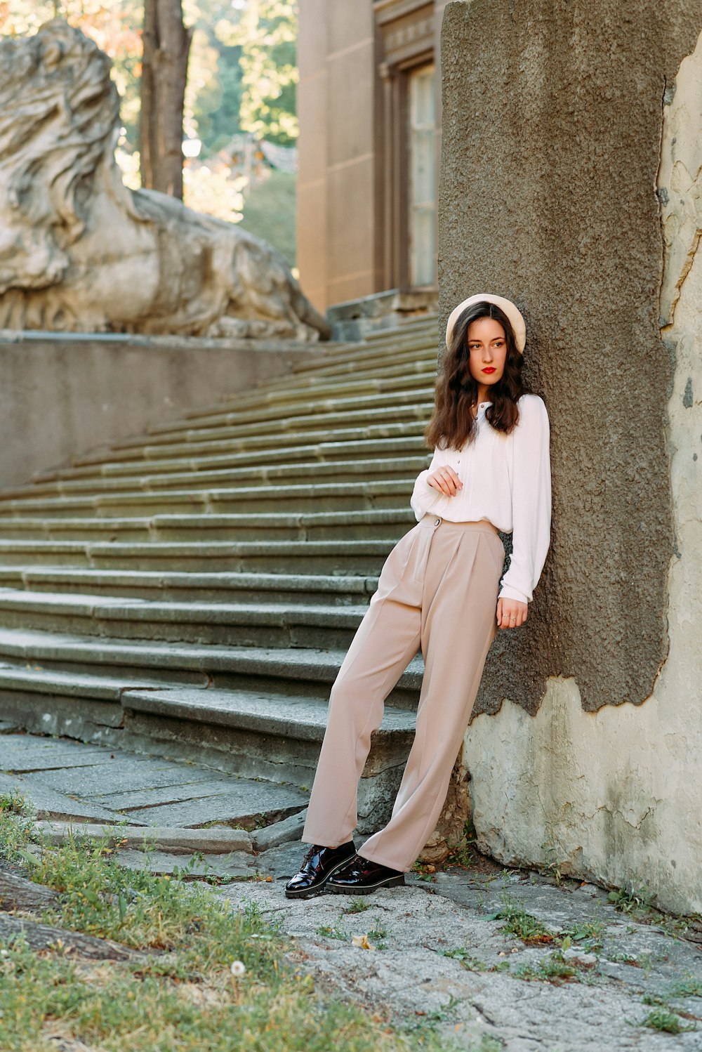 woman in white long sleeve shirt and brown pants standing on gray concrete stairs