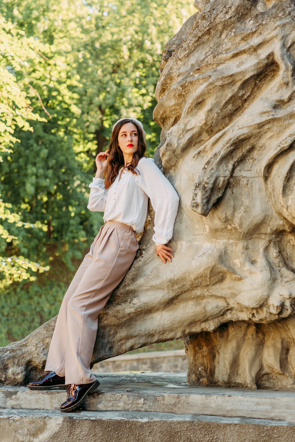 woman in white long sleeve dress leaning on brown rock