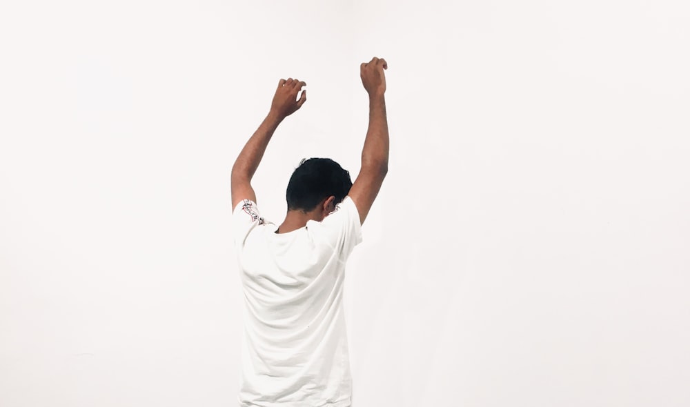 man in white t-shirt raising his hands