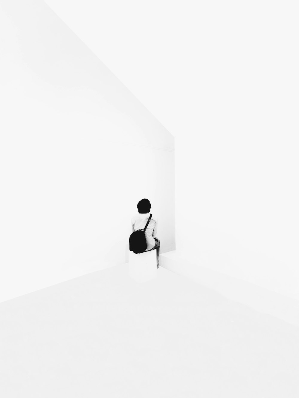 man in black suit standing on white wall