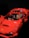 A red toy car resembling a sports car with a figure inside, featuring a yellow face and a helmet. The toy has intricate details, including side mirrors and an interior dashboard.