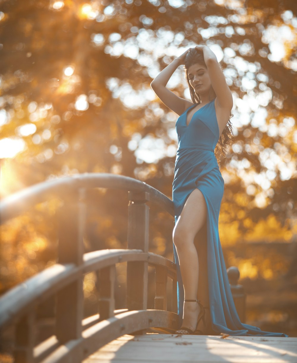 woman in blue sleeveless dress standing and raising her hands