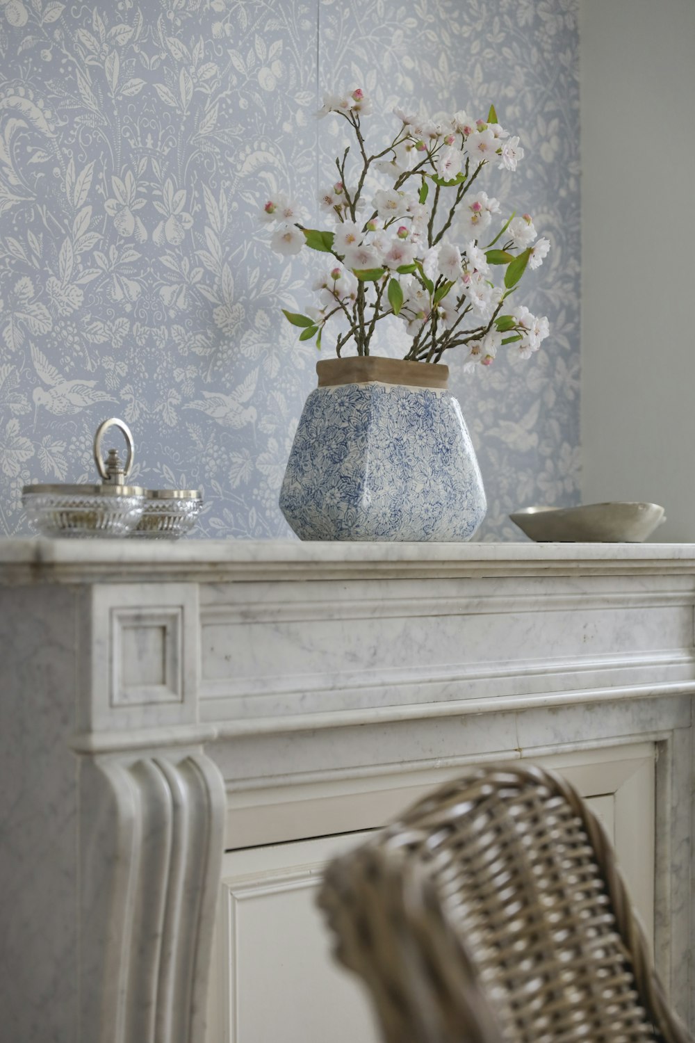 a vase with flowers in it sitting on a mantle