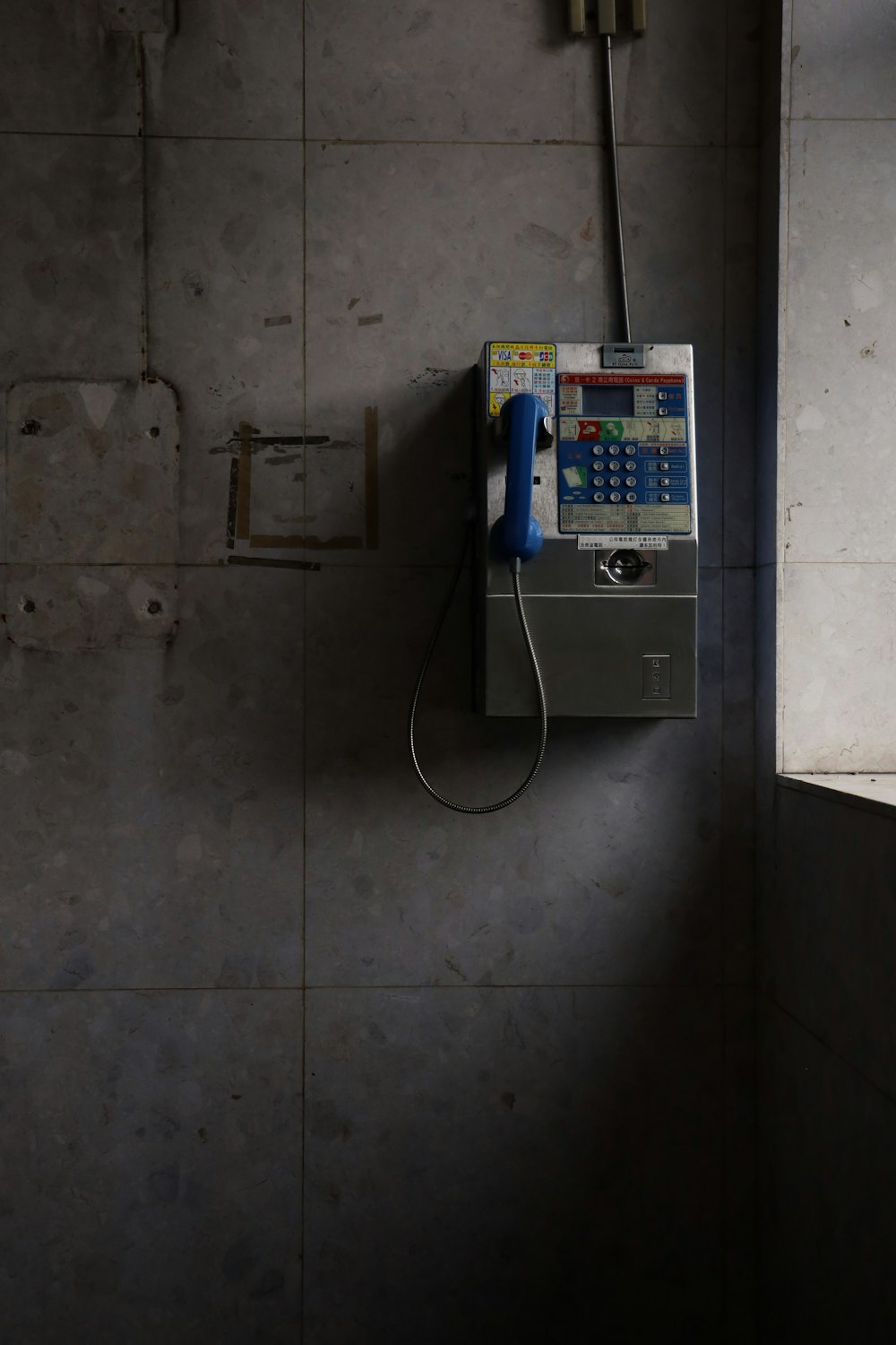 blue and white telephone mounted on gray wall