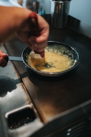 Artisan stirring fresh cream over a slow flame during the ghee-making process.