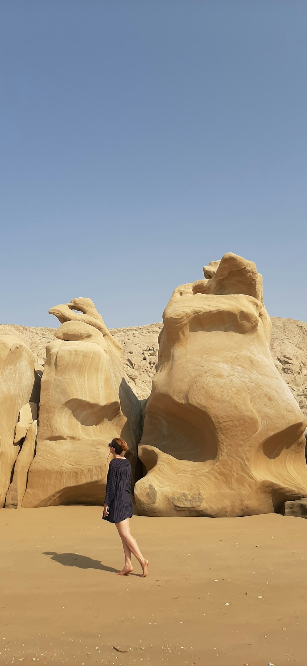 woman in black jacket sitting on brown rock formation during daytime