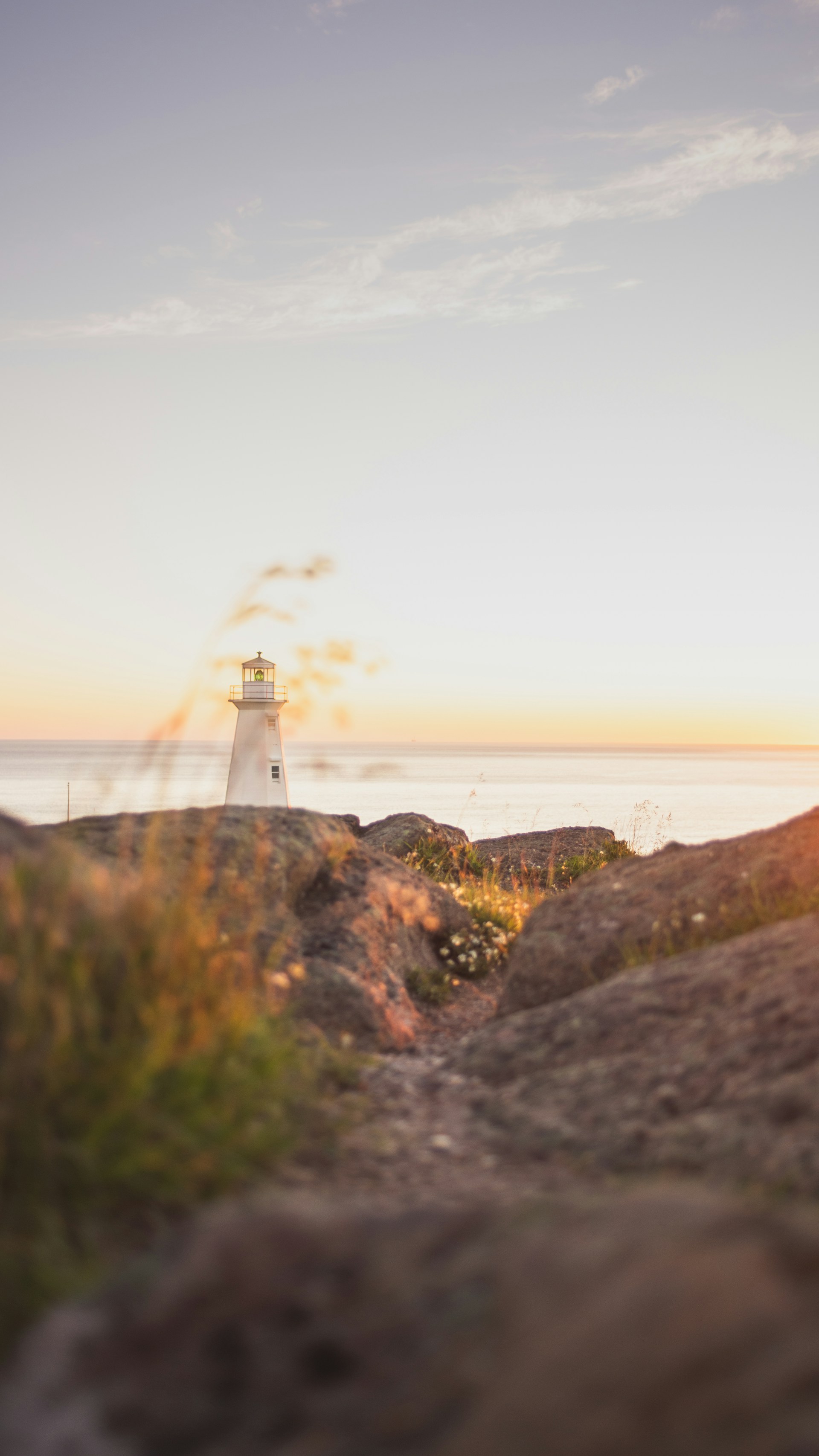 white lighthouse on top of hill near body of water during daytime