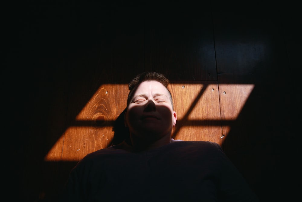 woman in black shirt lying on brown wooden bed