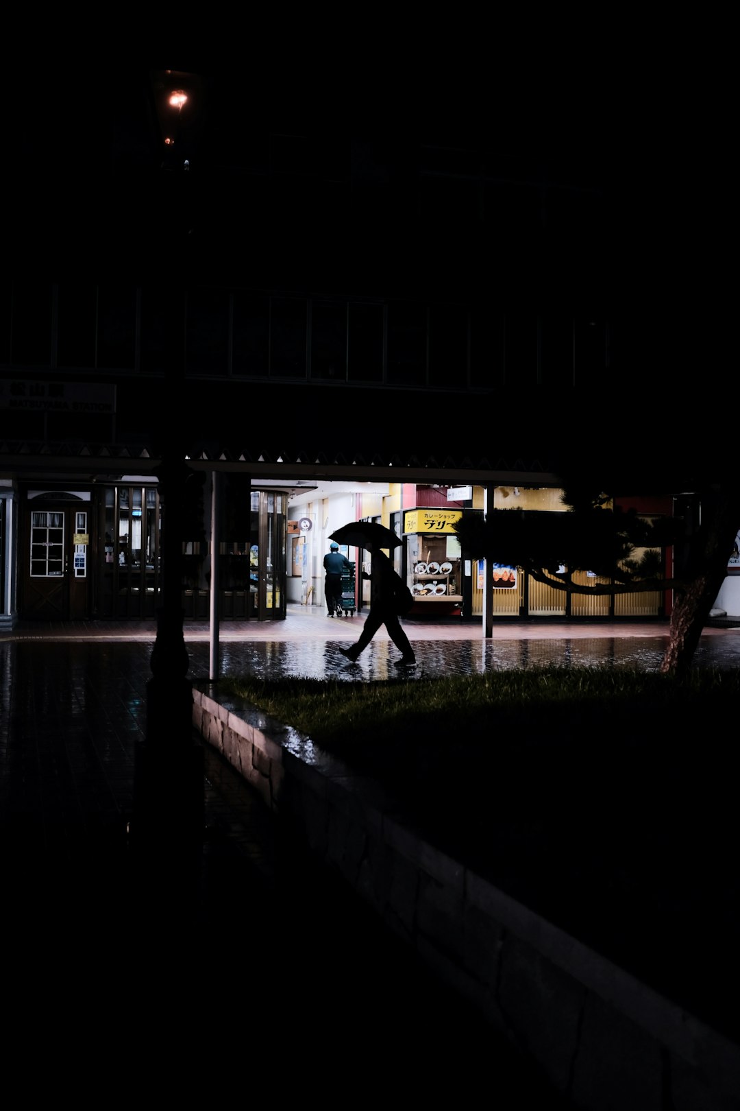 man in black jacket standing near building during night time