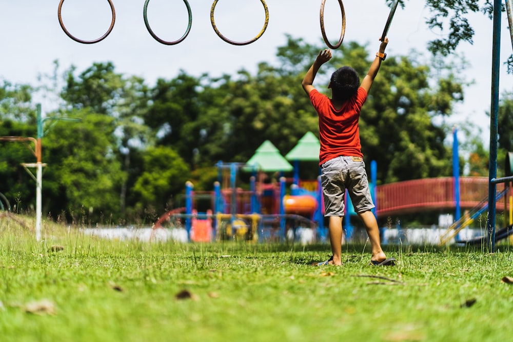 boy in red t-shirt and blue shorts playing basketball during daytime