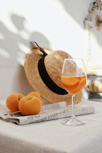orange fruit on brown woven basket beside clear wine glass