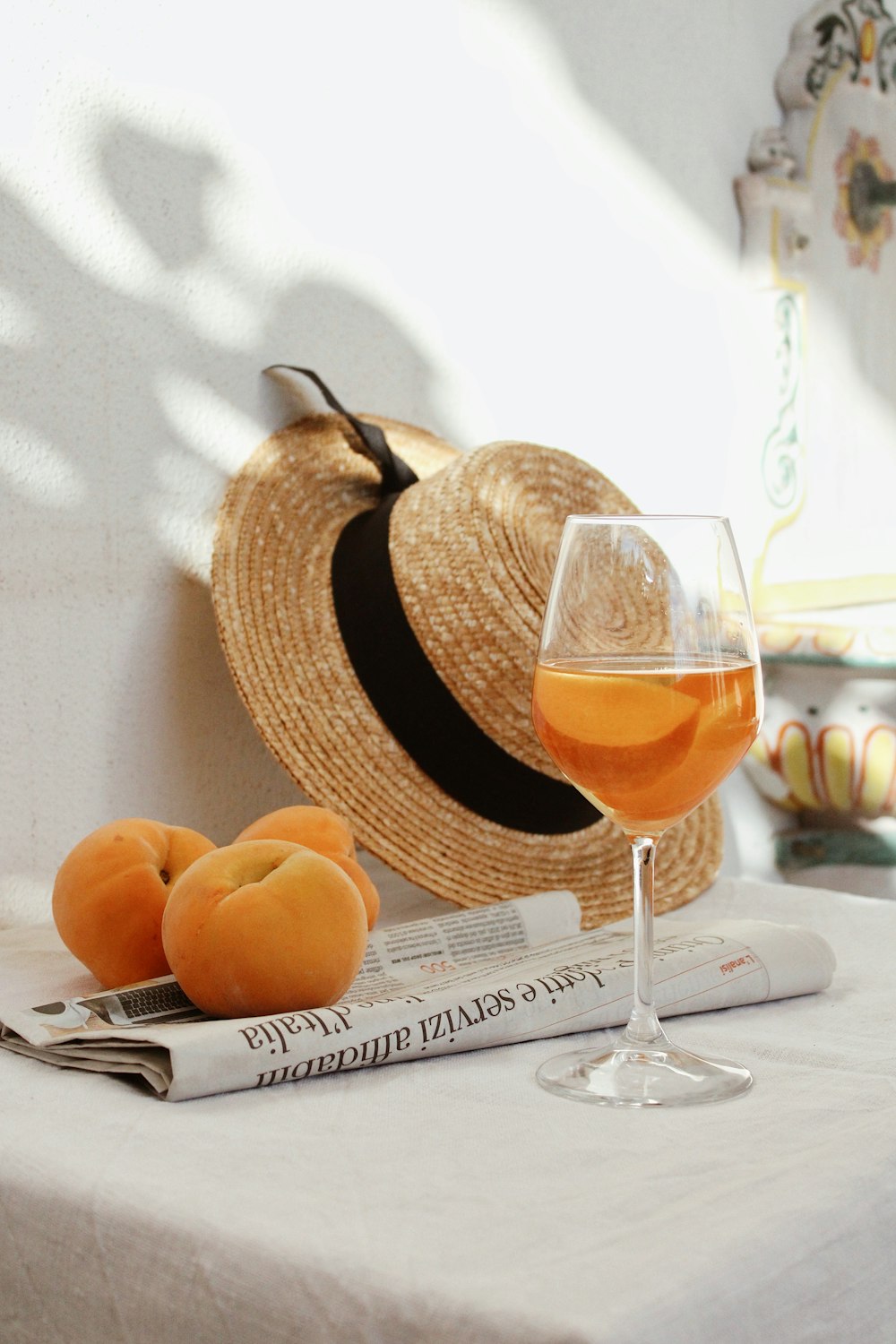 Frutta arancione su cesto intrecciato marrone accanto al bicchiere di vino trasparente