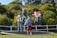Children laughing and bouncing high on a colorful elastic trampoline under a bright Swiss sky.