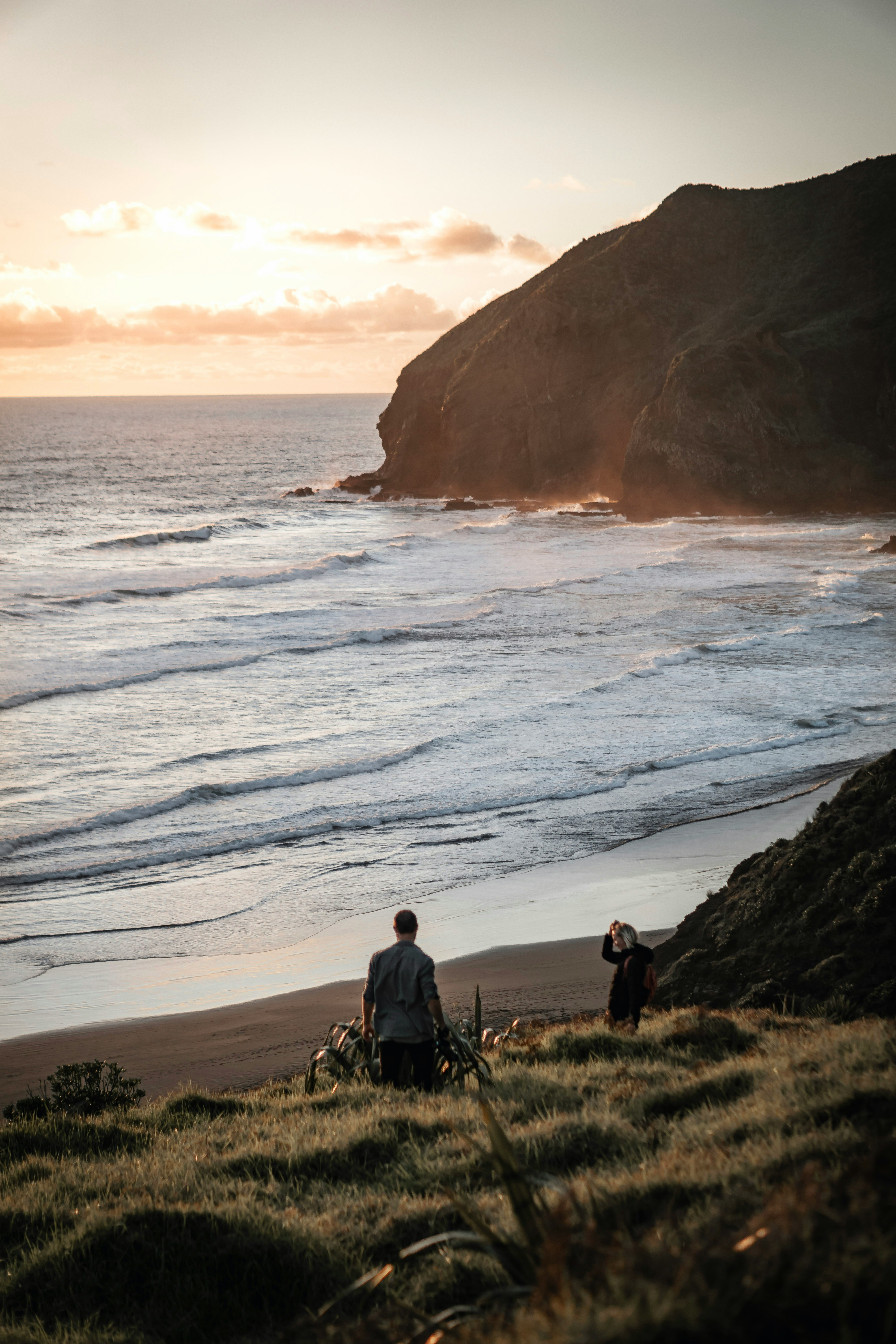 man and woman sitting on grass field near body of water during daytime