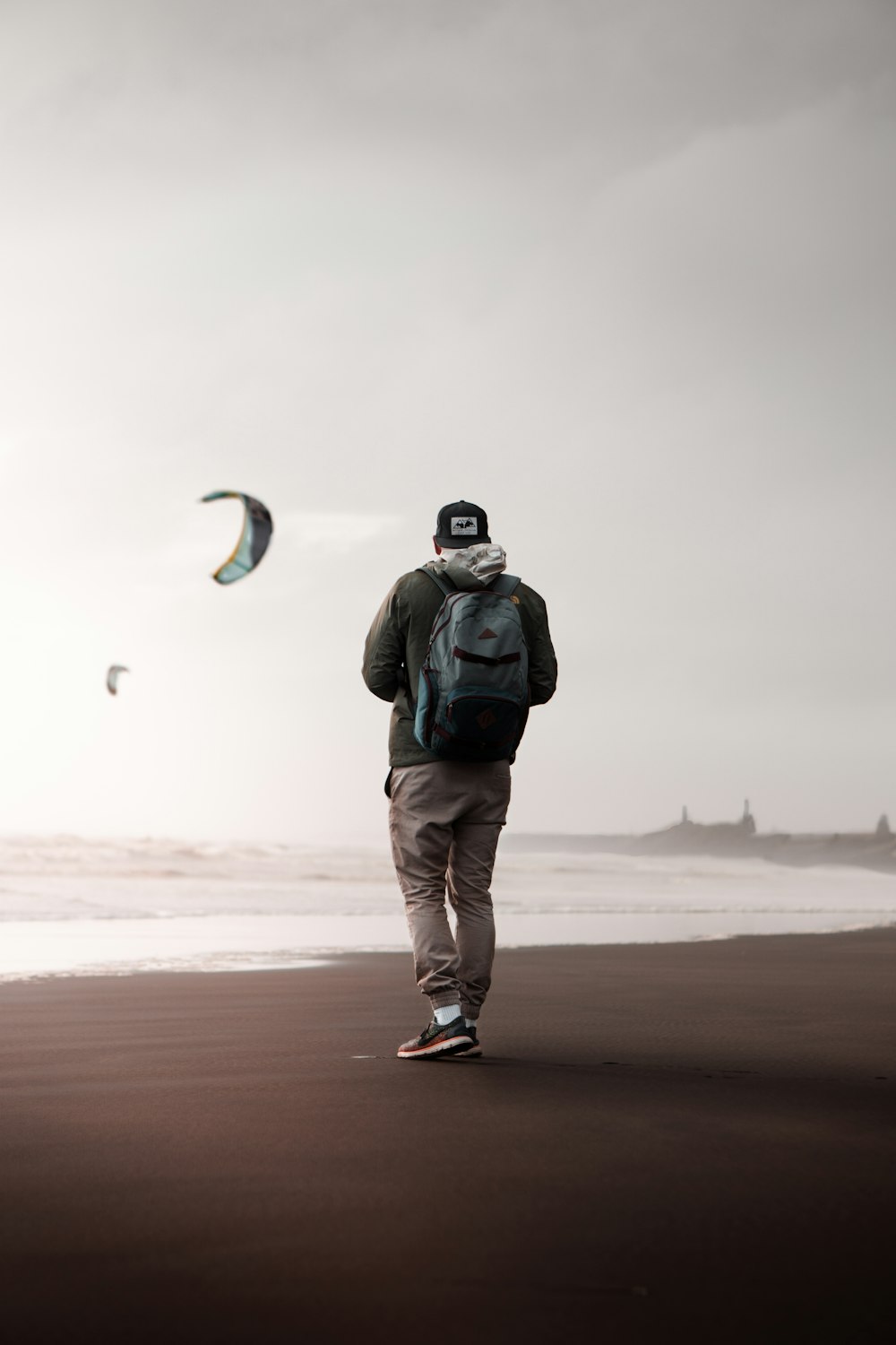 man in black jacket and white pants standing on beach during daytime