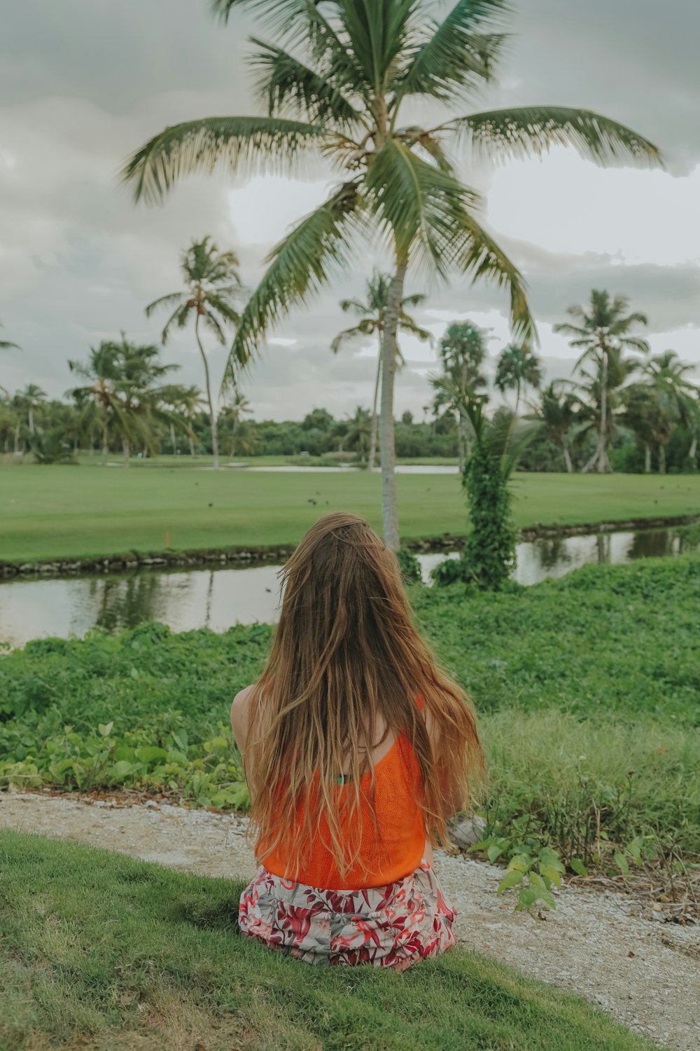 woman in orange shirt standing near body of water during daytime