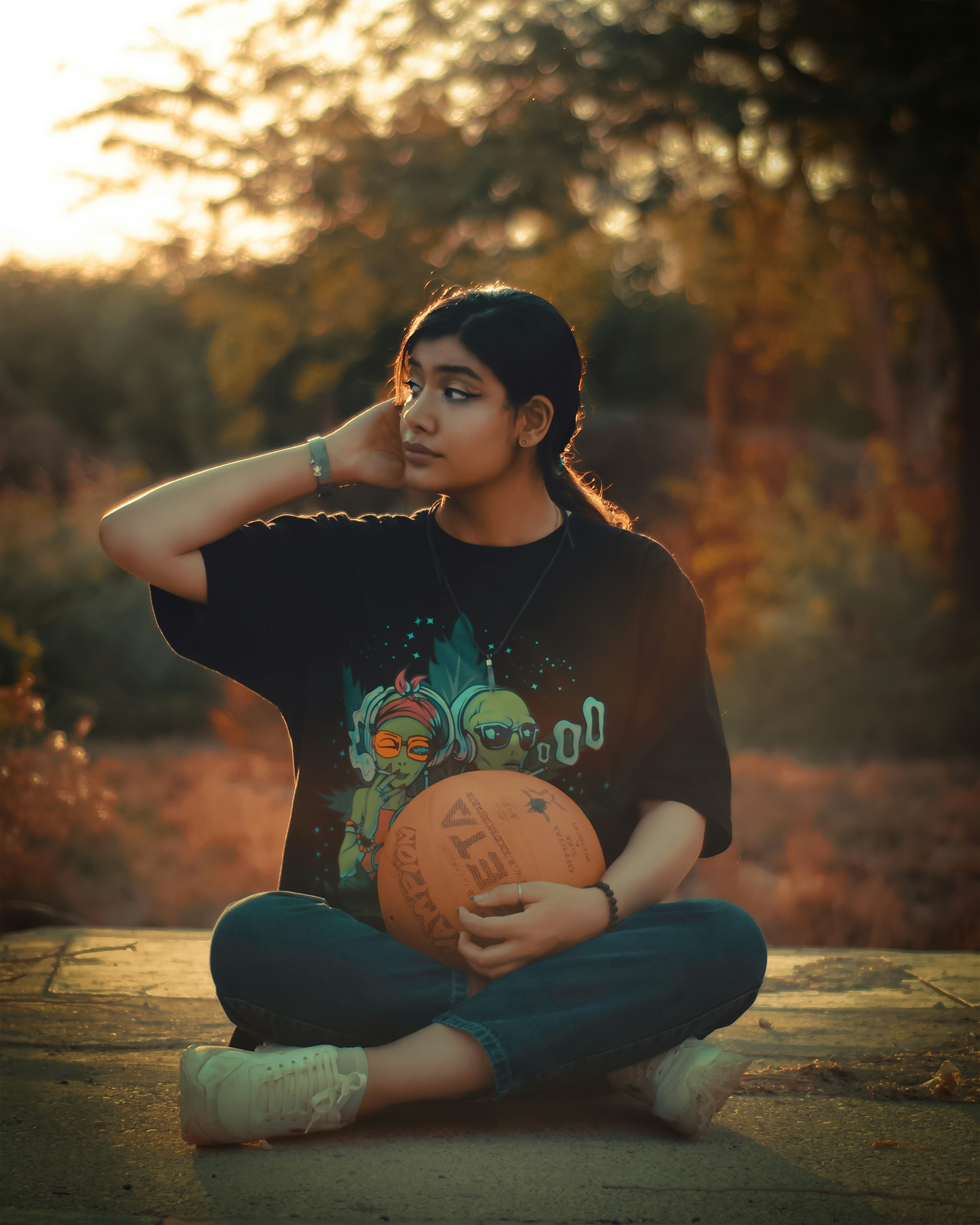 Wanita dengan kaos leher kru hitam dan jeans denim biru duduk di bangku kayu coklat